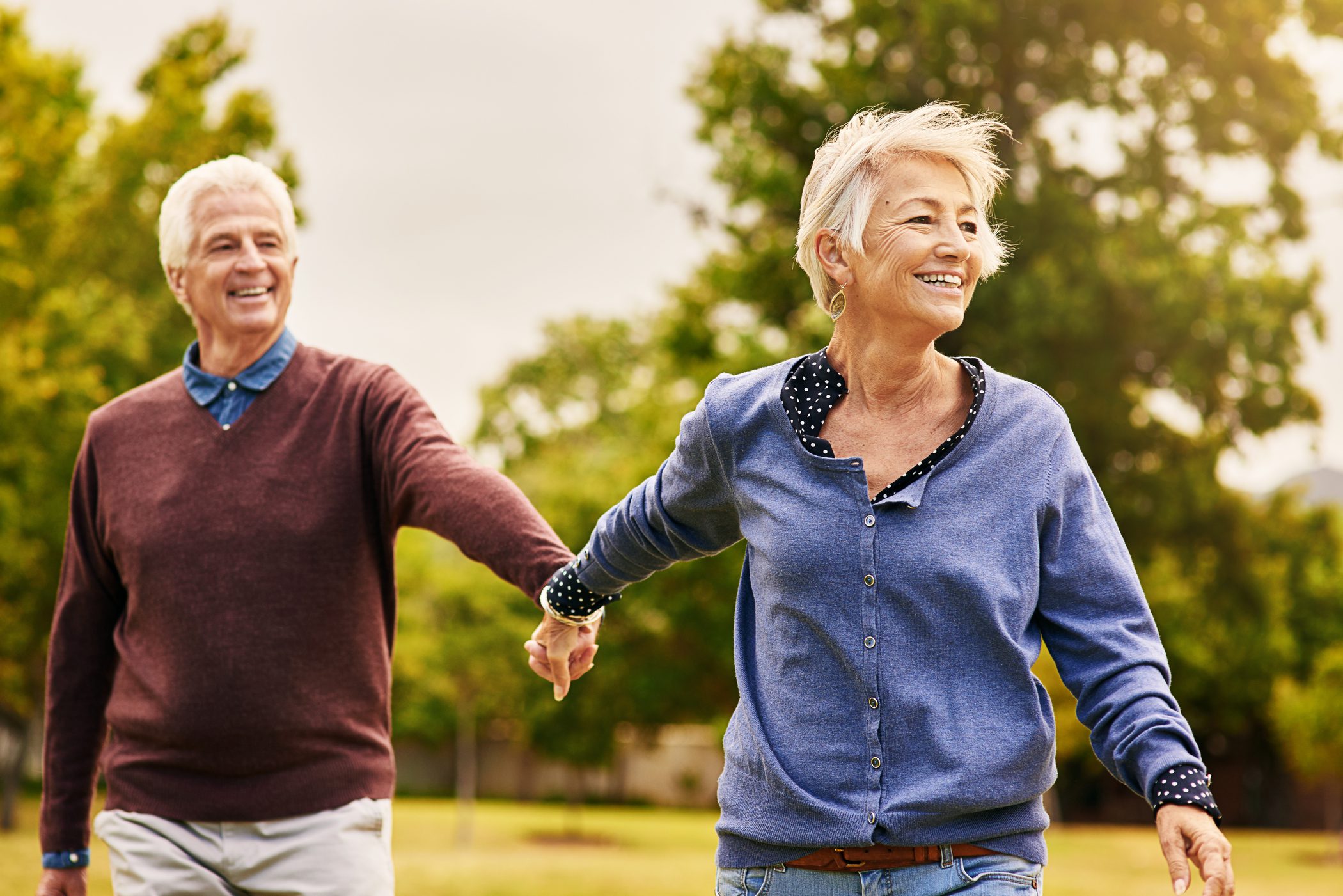 older couple holding hands and smiling in a park