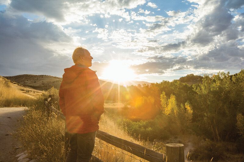 A person walking near a sunset with clouds in the sky.